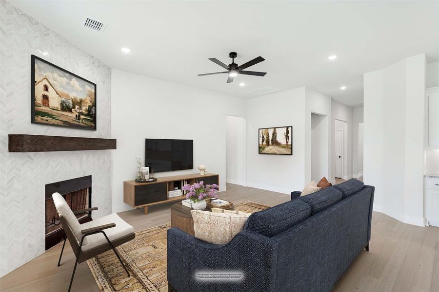 Living room with tiled fireplace, navy sofa, ceiling fan, and hardwood floors