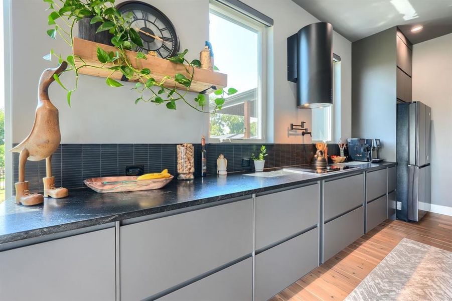 Kitchen featuring gray cabinets, light wood-style floors, freestanding refrigerator, modern cabinets, and backsplash Kitchen featuring gray cabinets, light wood-style floors, freestanding refrigerator, modern cabinets, and backsplash