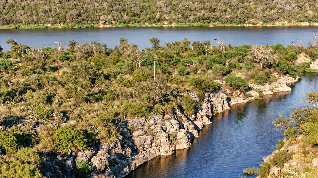 Drone / aerial community view of a nearby body of water and a heavily wooded area