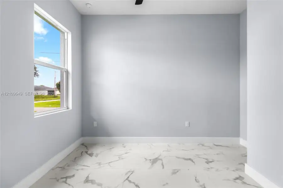 Interior space featuring large-format tile flooring with a marble-finish pattern, light-toned wall paint, and a single-hung window
