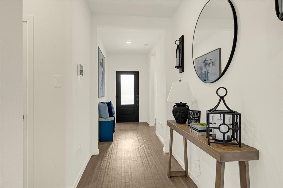 Bright and inviting hallway with sleek wood flooring, modern décor, and a stylish console table leading to a dark front door, creating an elegant entrance. Bright and inviting hallway with sleek wood flooring, modern décor, and a stylish console table leading to a dark front door, creating an elegant entrance.