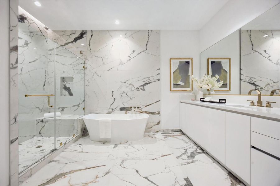 One of two primary baths, this space features large-format porcelain surfaces, a freestanding soaking tub, and a glass-enclosed shower, accented by French gold faucets and bath accessories. Both baths are thoughtfully separated by an expansive walk-in closet for added privacy and functionality.