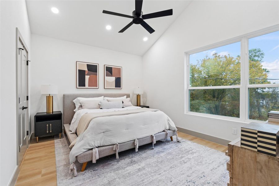 A peaceful primary retreat awaits—anchored by vaulted ceilings, wide-plank SPC flooring, and oversized windows that fill the space with natural light. The clean, modern aesthetic offers a calming backdrop for rest, recharge, and everyday luxury.