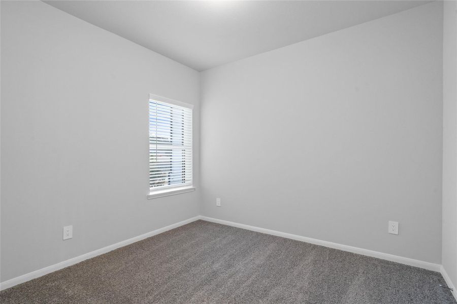 This cozy secondary bedroom offers plush soft carpeting, neutral walls ready for personalization, a sun-filled window with fitted blinds, sloped ceilings, and a spacious closet for all your storage needs.