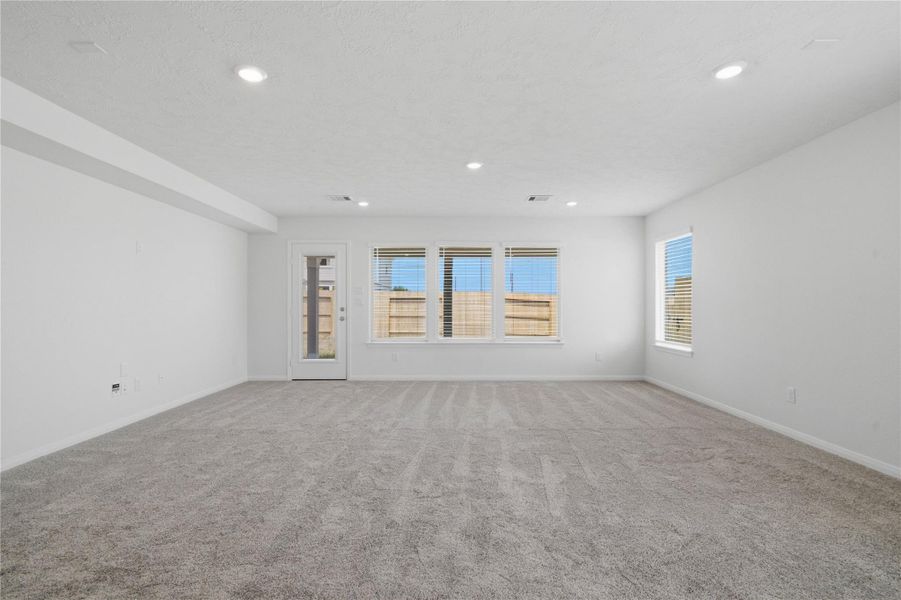 This bright and airy Great Room offers a spacious layout ideal for both relaxing evenings and lively gatherings. Designed for comfort and connection, it features plush carpet flooring, large windows with blinds, soaring ceilings, recessed lighting, and seamless access to the stunning kitchen and dining—perfect for everyday living and entertaining alike.