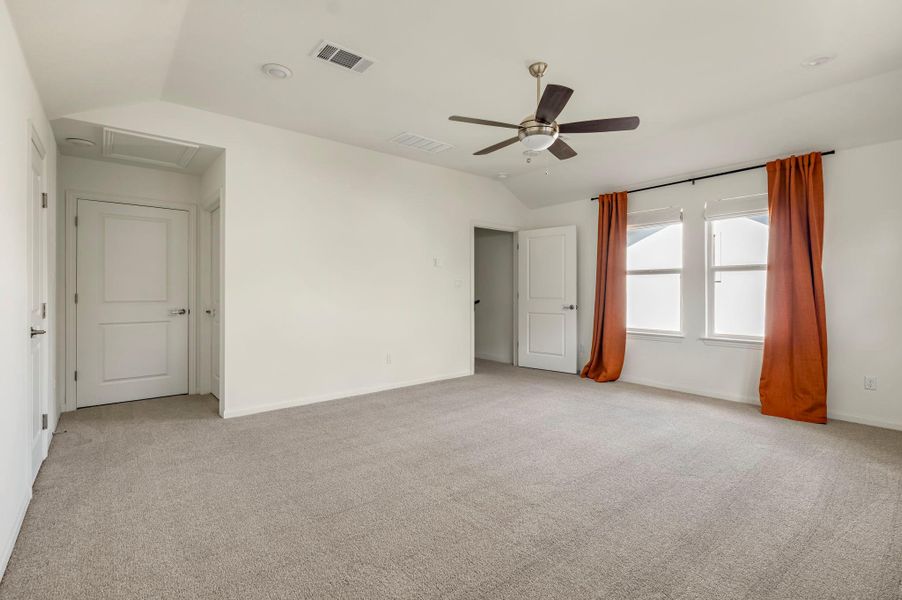Upstairs bedroom with vaulted ceiling, attic access, light colored carpet, and a ceiling fan Upstairs bedroom with vaulted ceiling, attic access, light colored carpet, and a ceiling fan