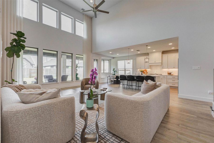 Lliving area features high ceilings and abundant natural light from large windows. It seamlessly connects to a modern kitchen with white cabinetry and a large island, creating a perfect space for entertaining. Lliving area features high ceilings and abundant natural light from large windows. It seamlessly connects to a modern kitchen with white cabinetry and a large island, creating a perfect space for entertaining.