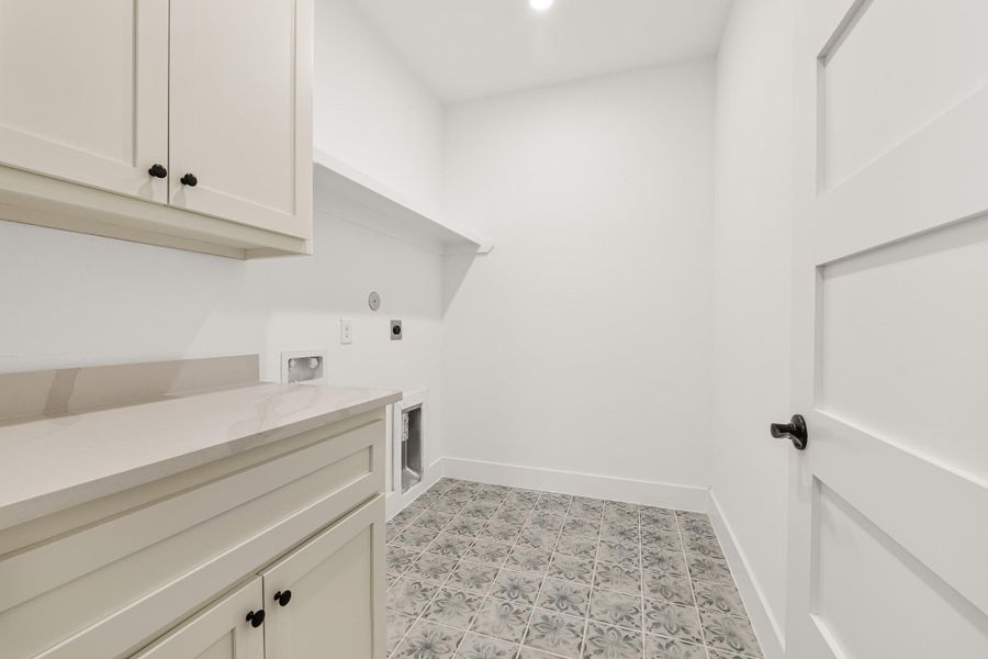 This is a bright, well-organized laundry room featuring patterned tile flooring, cabinetry with countertop space, and hookups for a washer and dryer. This is a bright, well-organized laundry room featuring patterned tile flooring, cabinetry with countertop space, and hookups for a washer and dryer.