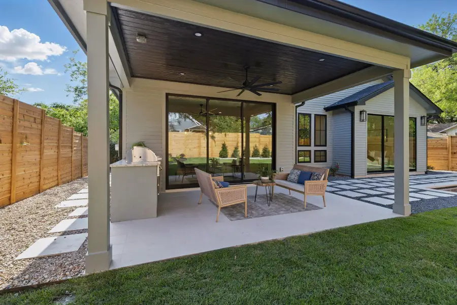 Fenced backyard with a ceiling fan, a patio, an outdoor hangout area, and exterior kitchen