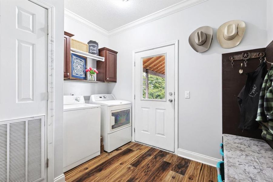 Laundry room featuring cabinets, independent washer and dryer, dark hardwood / wood-style flooring, and crown molding