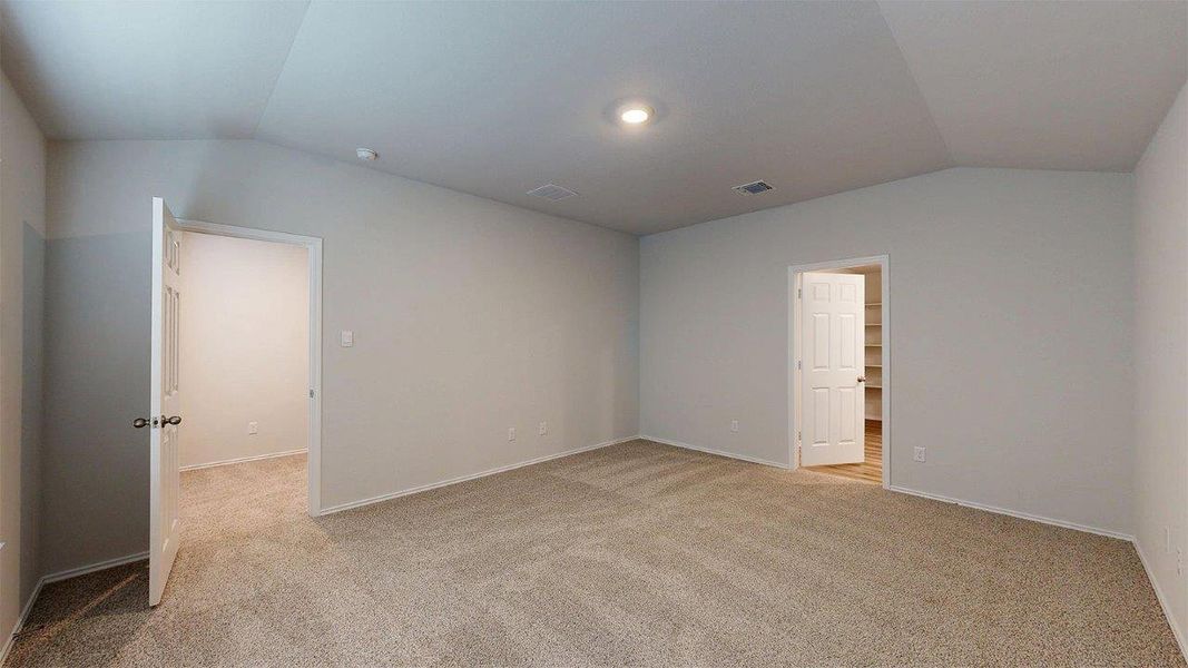 Spacious room featuring vaulted ceilings, neutral-toned carpeting, and a recessed light fixture Spacious room featuring vaulted ceilings, neutral-toned carpeting, and a recessed light fixture