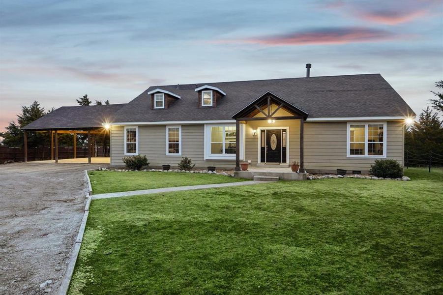 View of front of property with a carport and a yard