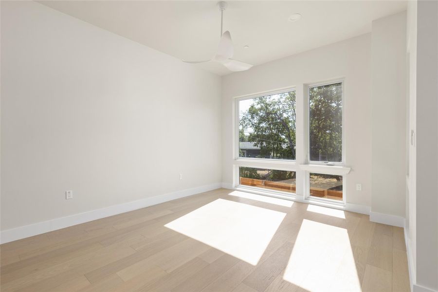 Sunlight streams across the smooth wood floors of this airy and minimalist bedroom.