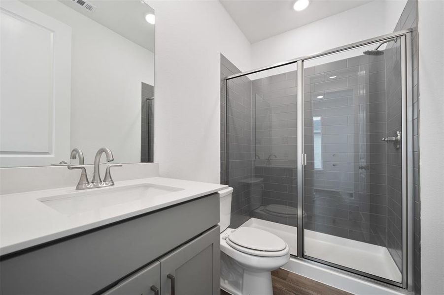 Bathroom featuring walk in shower, toilet, vanity, and hardwood / wood-style flooring