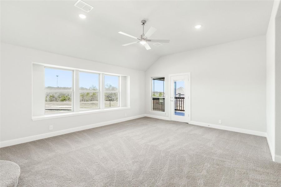 Spacious bedroom with vaulted ceiling, ceiling fan, carpet, large windows, and French doors to a balcony Spacious bedroom with vaulted ceiling, ceiling fan, carpet, large windows, and French doors to a balcony