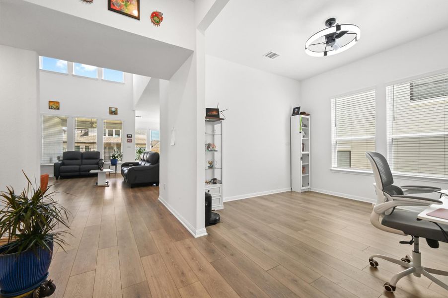 Warm wood flooring and high ceilings connect this versatile space to the adjoining living room.