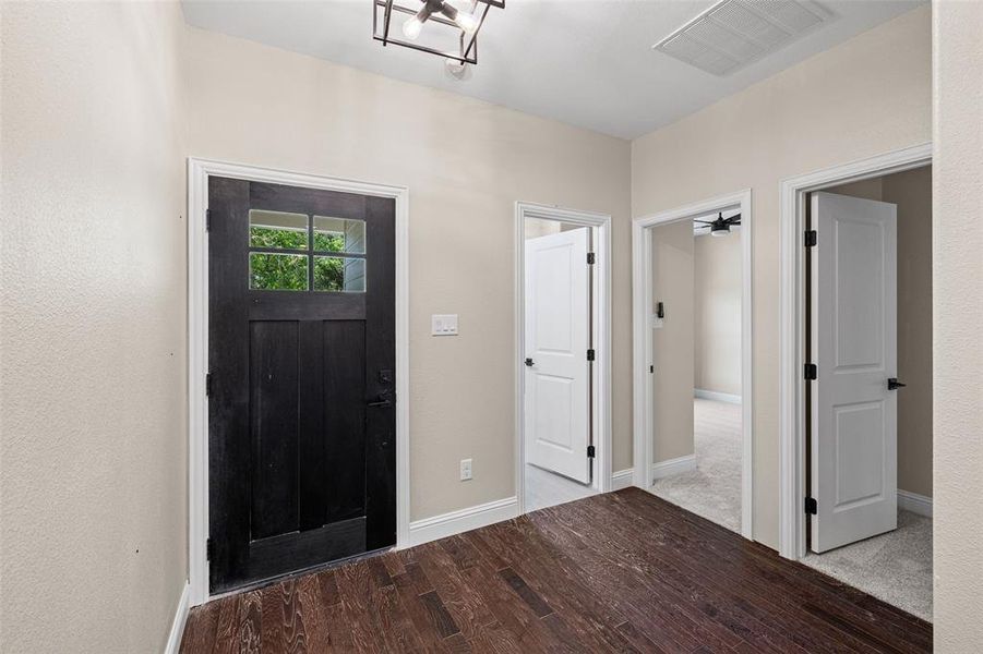 Entryway featuring a dark wood-finish door with glass panels, wood-finish flooring, light neutral walls, and a modern ceiling light fixture