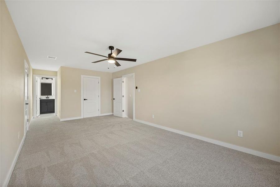 Unfurnished bedroom with connected bathroom, ceiling fan, and light colored carpet