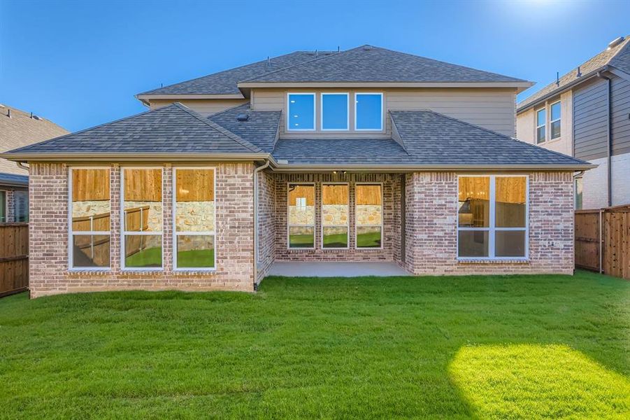 Rear view of house featuring a shingled roof, brick siding, and a patio area
