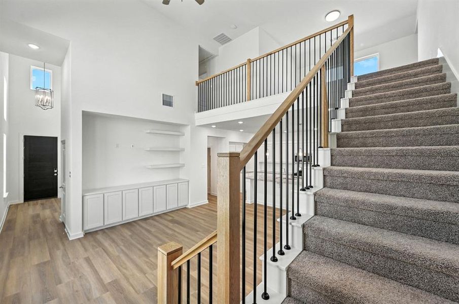 Staircase featuring wood finished floors, recessed lighting, and a towering ceiling