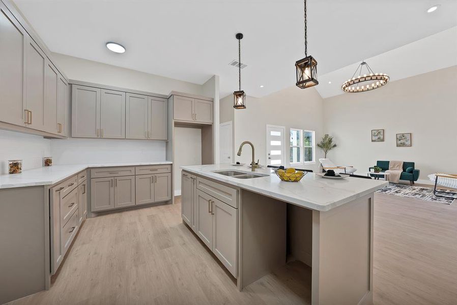 Kitchen featuring gray cabinetry, light wood-style flooring, light stone counters, hanging light fixtures, and lofted ceiling