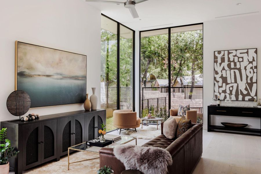 Living room featuring floor to ceiling windows, wood finished floors, and a ceiling fan Living room featuring floor to ceiling windows, wood finished floors, and a ceiling fan