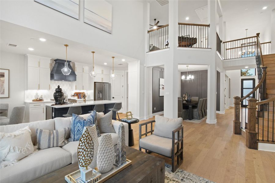 Living area with light wood-style floors, stairway, recessed lighting, a high ceiling, and a chandelier