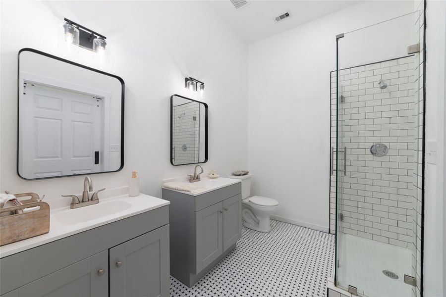 This modern bathroom features a spacious glass-enclosed shower, dual vanities with sleek black mirrors, and stylish lighting. This modern bathroom features a spacious glass-enclosed shower, dual vanities with sleek black mirrors, and stylish lighting.