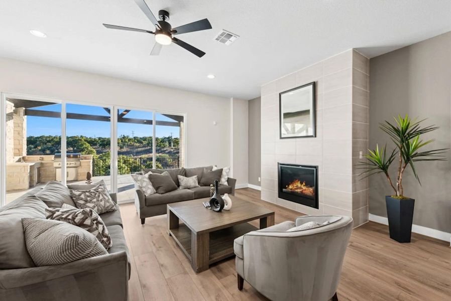 Living area with a tile fireplace, light wood finished floors, recessed lighting, and ceiling fan Living area with a tile fireplace, light wood finished floors, recessed lighting, and ceiling fan