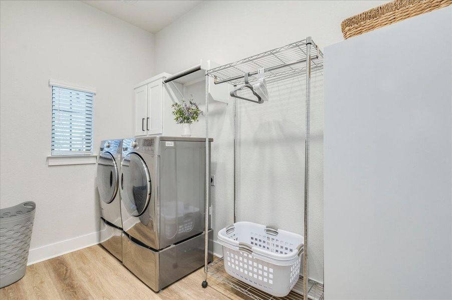 Laundry area featuring light wood-style floors, separate washer and dryer, and cabinet space Laundry area featuring light wood-style floors, separate washer and dryer, and cabinet space