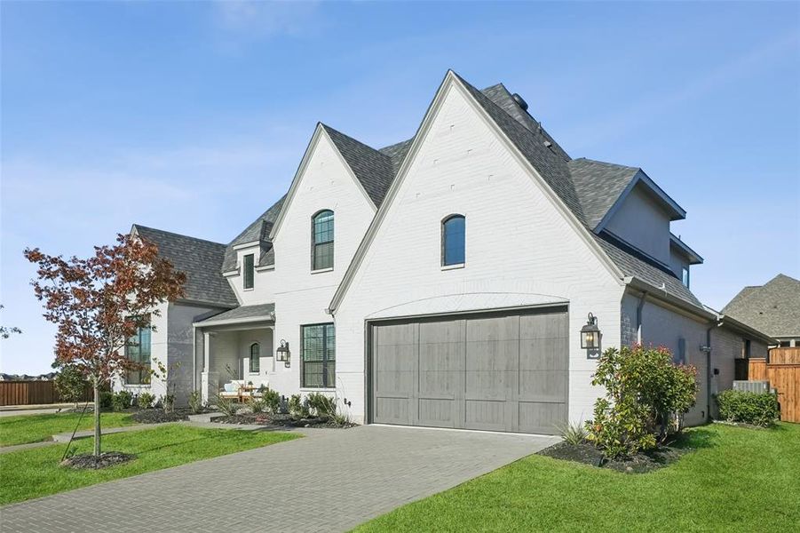 View of front of house with decorative driveway, a shingled roof, brick siding, and a porch View of front of house with decorative driveway, a shingled roof, brick siding, and a porch