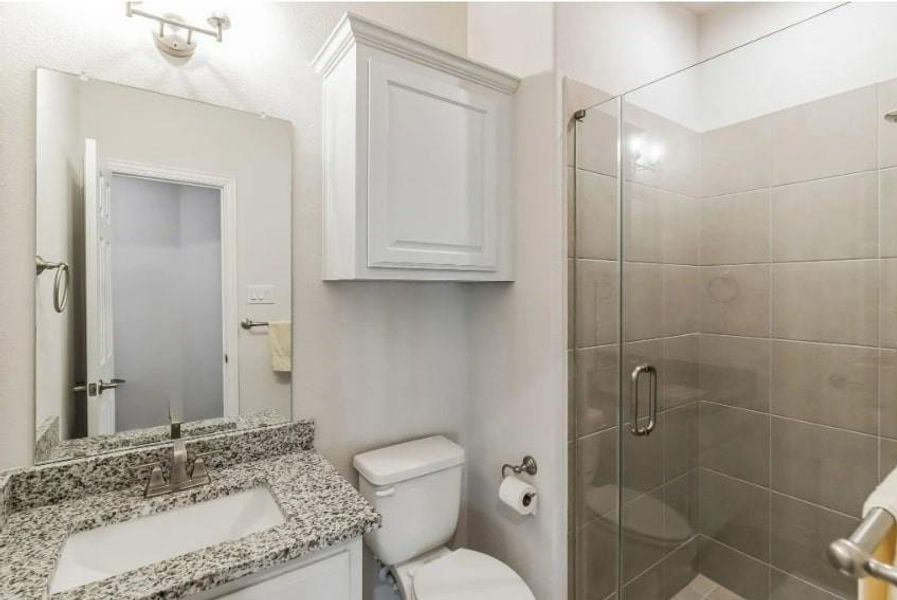 Bathroom with a shower with door, vanity, and toilet