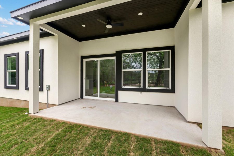 Expansive covered patio featuring a dark wood-finish ceiling, recessed lighting, and a ceiling fan