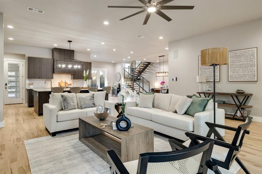 Living room featuring ceiling fan with notable chandelier and light hardwood / wood-style flooring