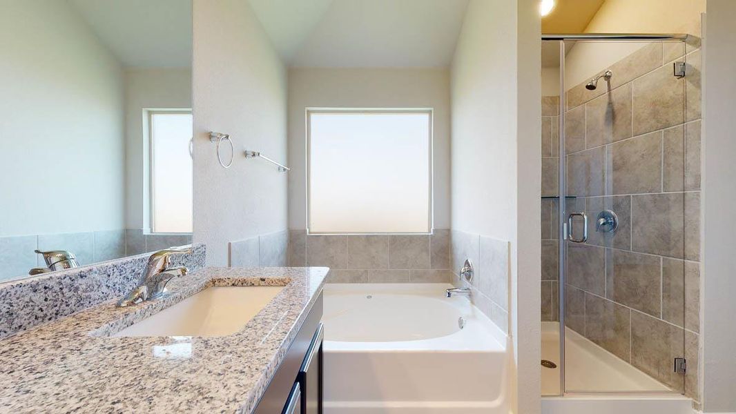Bathroom featuring a granite-look vanity with an integrated sink, a white tub with tiled surround, and a glass-enclosed shower with tiled walls