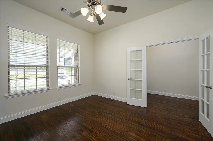 Spare room featuring dark wood-type flooring, french doors, and ceiling fan