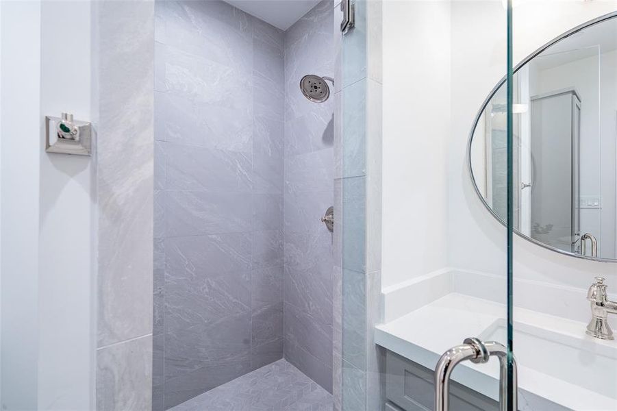 Bathroom with vanity and tiled shower