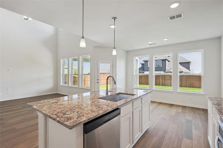 Kitchen featuring sink, stainless steel dishwasher, an island with sink, plenty of natural light, and hardwood / wood-style flooring