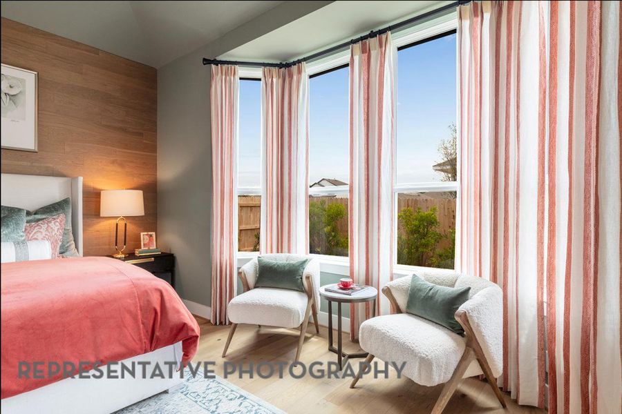 Bedroom featuring wooden walls, multiple windows, wood finished floors, and an accent wall Bedroom featuring wooden walls, multiple windows, wood finished floors, and an accent wall