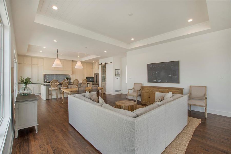 Living room featuring dark hardwood flooring and a tray ceiling