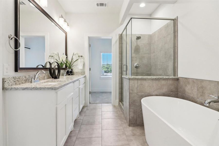 Bathroom with tile patterned flooring, shower with separate bathtub, and vanity