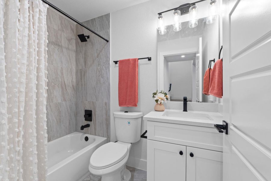 Modern stone tile detailing accents the shower and tub area adjacent to a sleek vanity.