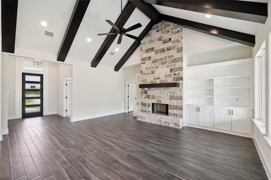 Unfurnished living room with a fireplace, ceiling fan, built in shelves, dark hardwood / wood-style flooring, and beam ceiling