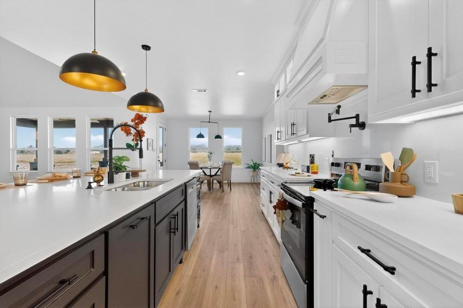 Kitchen featuring two tone cabinetry, range with electric stovetop, pendant lighting, light wood-style flooring, and light stone countertops Kitchen featuring two tone cabinetry, range with electric stovetop, pendant lighting, light wood-style flooring, and light stone countertops