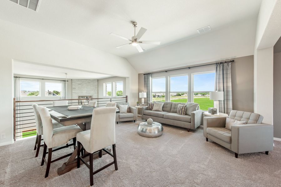 Open-concept living and dining area with vaulted ceiling, ceiling fan, gray carpet, and large windows with outdoor views.