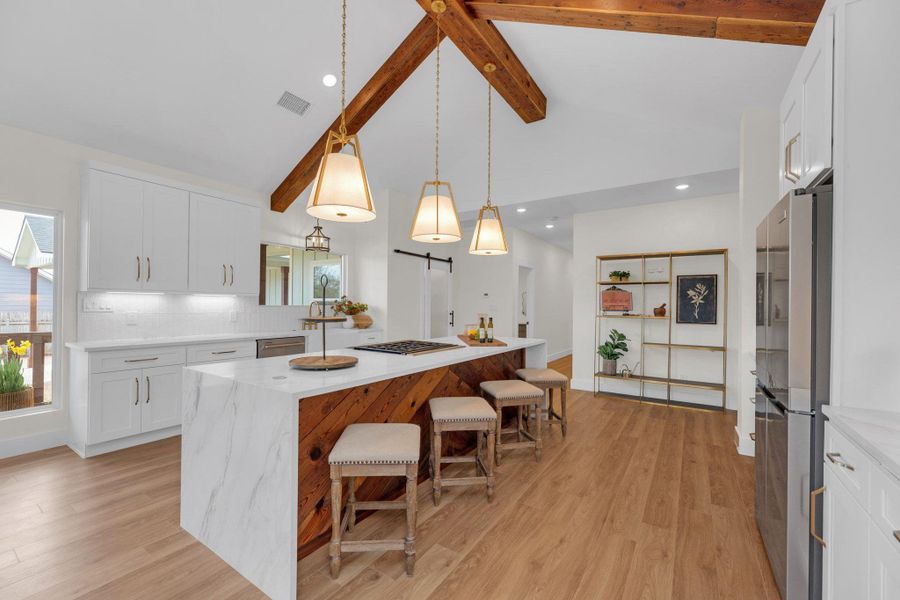 Appointed with reclaimed cedar beams and chevron detail on kitchen Island, wood from original historic home. Glass barn door on pantry. Whirlpool refrigerator. Calacatta Castana Quartz Countertops.
