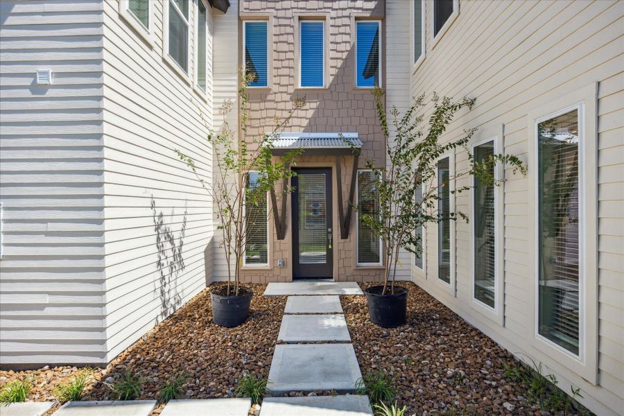 The front entrance offers a clean, contemporary welcome with a concrete stepping path framed by thoughtfully designed low-maintenance landscaping.