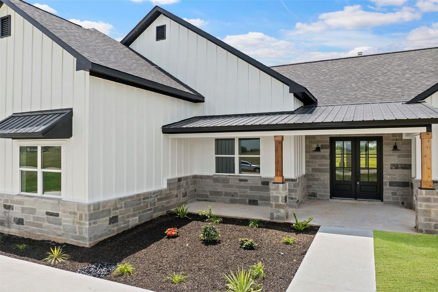Charming modern farmhouse with inviting front porch, elegant black accents, and fresh landscaping.