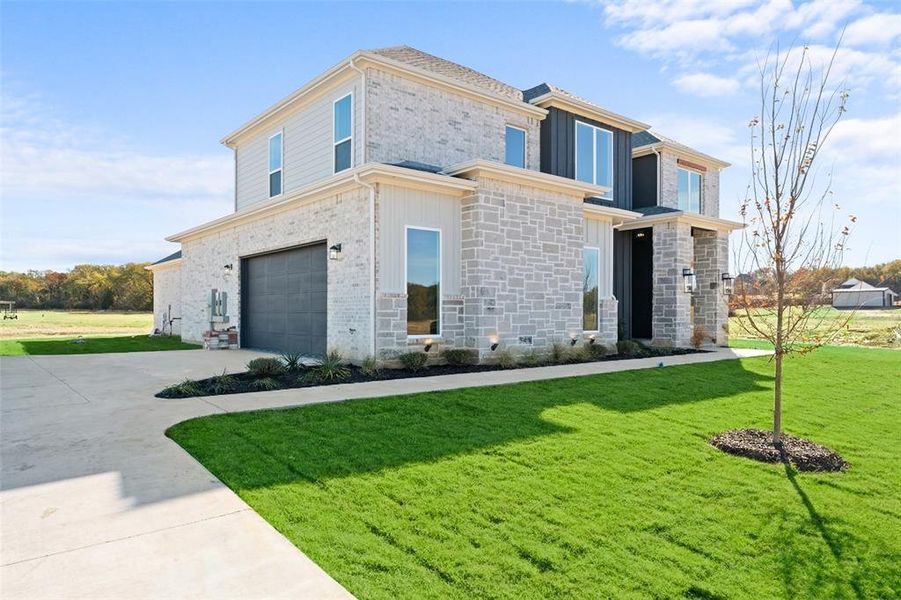 View of front of house with a front yard, driveway, a garage, and stone siding View of front of house with a front yard, driveway, a garage, and stone siding