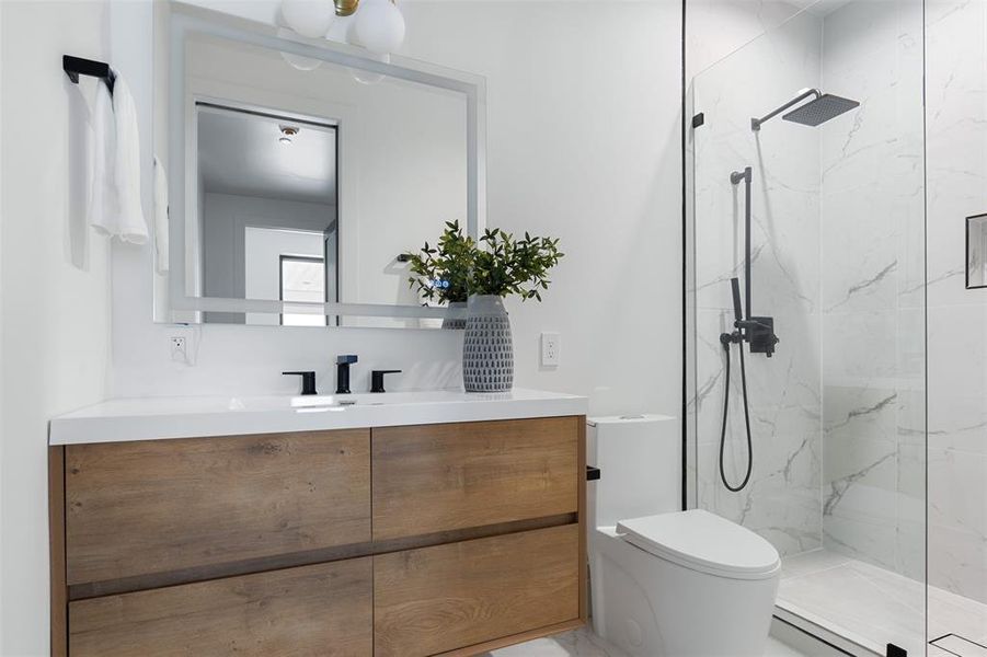 Bathroom with tile patterned floors, vanity, a tile shower, and toilet